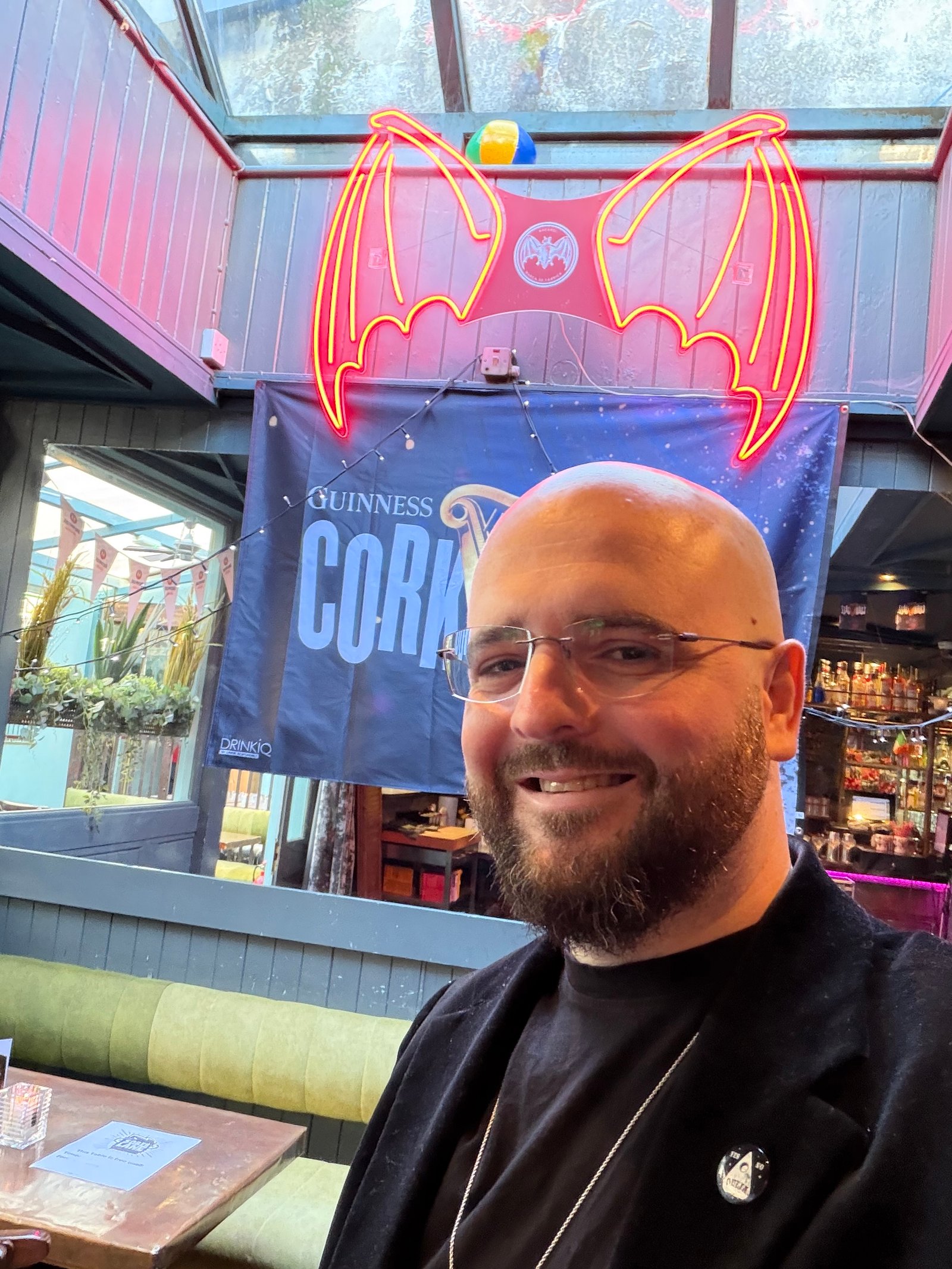 David Peace under the red neon bat and Guinness Cork banner at Sober Lane