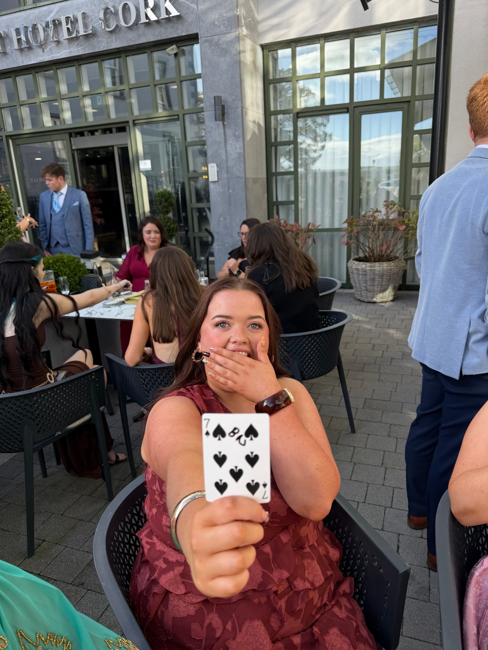 A guest laughing behind a seven and eight of spades on the patio at the front of the Talbot Hotel Cork