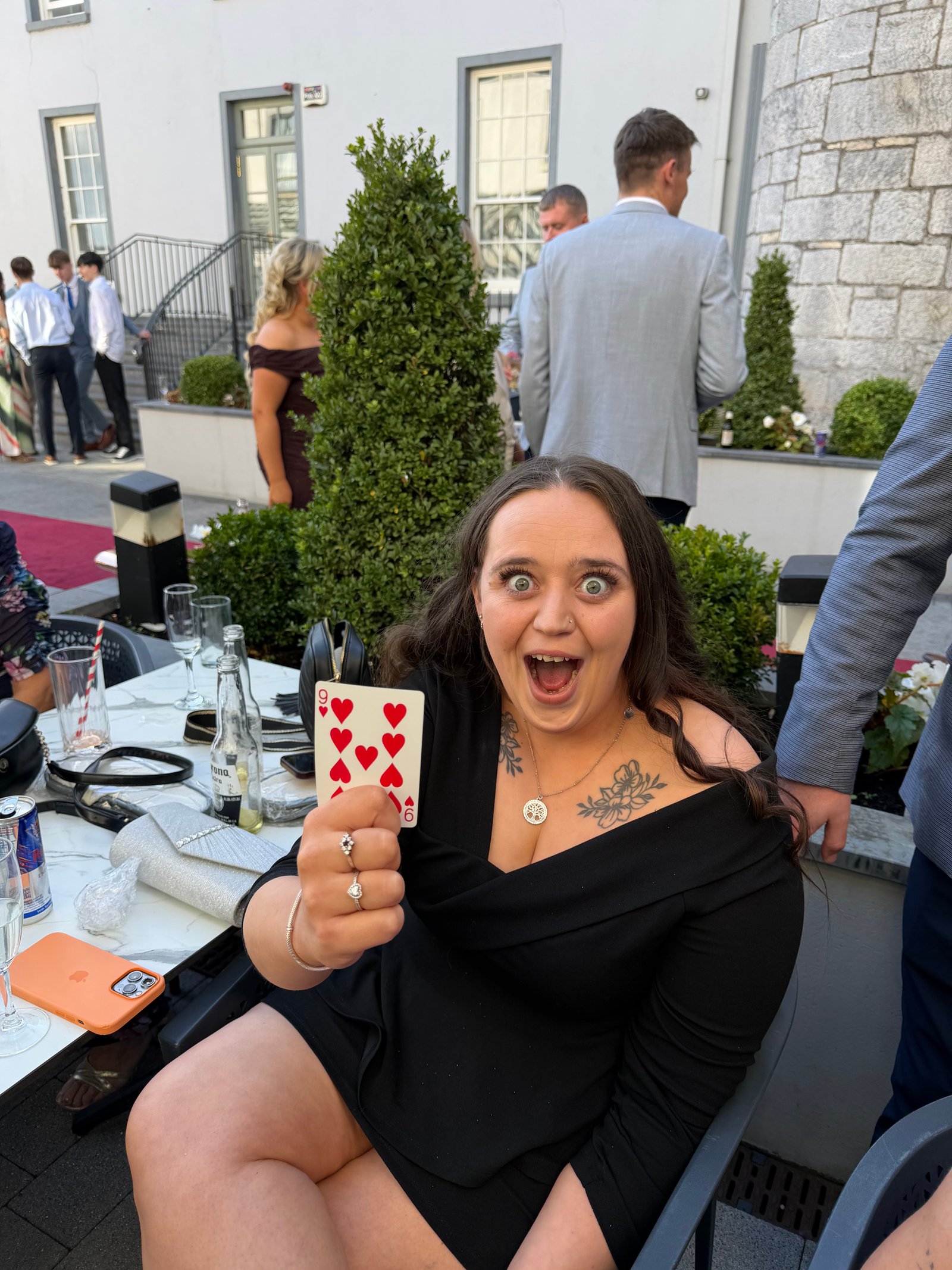 A guest holding up the nine of hearts during close-up magic on the patio at the front of the Talbot Hotel Cork
